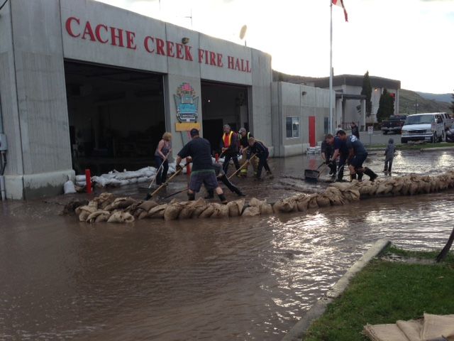 Firefighters pile up sandbags in an effort to control the flow of water at the Cache Creek Fire Hall on May 5, 2017.