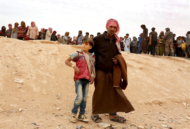 In this May 4, 2016 file photo, a Syrian refugee man and boy cross into Jordan at the Hadalat reception area on the Syrian-Jordanian border, northeast of the capital, Amman.