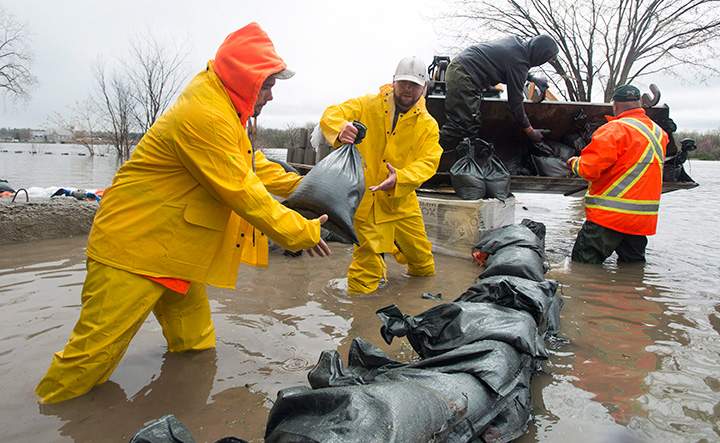 Men work to shore up a wall of sandbags surrounding a home in a flooded area of Gatineau, Que. Sunday May 7, 2017.