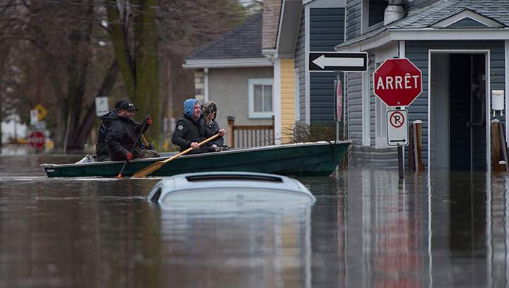Local residents paddle a boat past a submerged car in a flooded area of Gatineau, Que. Sunday May 7, 2017.