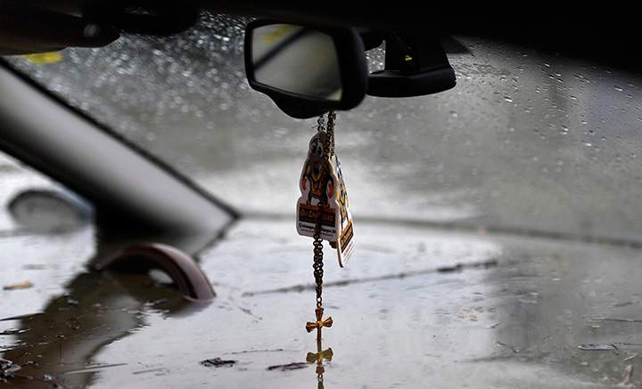 Floodwaters touch the bottom of a crucifix hanging from the rear view mirror of a car abandoned on a residential street in Gatineau, Que., on Saturday, May 6, 2017.
