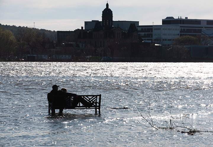 This couple did not have to fight for a seat since they were the only ones to wade through the flood water from the St. John River to get to this bench in Carleton Park on the north side of Fredericton, NB, on Sunday, May 7, 2017.
