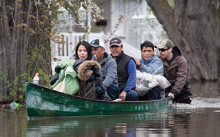 Family members are helped with some their belongings after being evacuated from their home in the Montreal borough of Pierrefonds, Sunday, May 7, 2017, following flooding in the region.