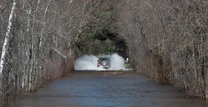 A vehicle drives on a flooded street in Fredericton, N.B., on Sunday, May 7, 2017.