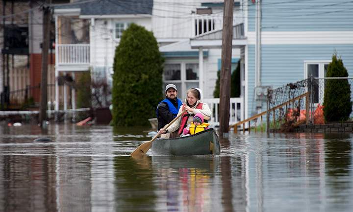 People paddle a canoe through the floodwaters, Sunday May 7, 2017 in Gatineau, Que.