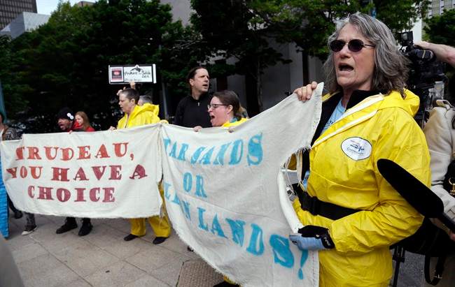 A small group of demonstrators protesting Canada’s Trans Mountain Pipeline expansion chant as Canada Prime Minister Justin Trudeau leaves a hotel steps away following a meeting Thursday, May 18, 2017, in Seattle.