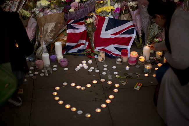A British flag is seen next to flowers after a vigil in Albert Square, Manchester, England, Tuesday May 23, 2017, the day after the suicide attack at an Ariana Grande concert.