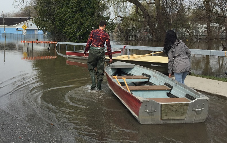 A man and woman prepare to launch a small boat into the street near the rising Gatineau River on Thursday, May 4, 2017.