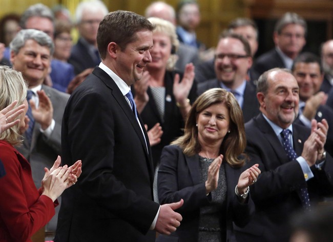 Conservative Leader Andrew Scheer is all smiles when he receives a standing ovation from Rona Ambrose and other members of parliament in the House of Commons on Monday.