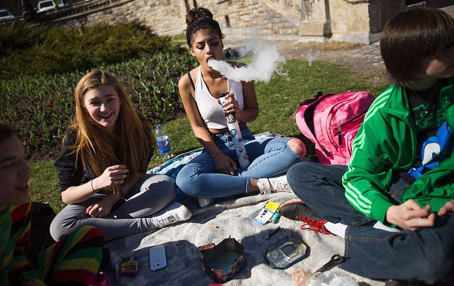 A woman blows smoke as another looks on as thousands gathered to celebrate National Marijuana Day in Ottawa on April 20, 2016.  