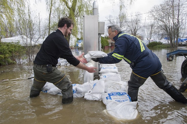 Volunteers place sandbags around an electrical panel in the town of Hudson, Que., west of Montreal, Monday, May 8, 2017, following flooding in the region. Rain scheduled for the weekend could make matters worse for flooded areas, especially in the Mauricie. Thursday, May 11, 2017.