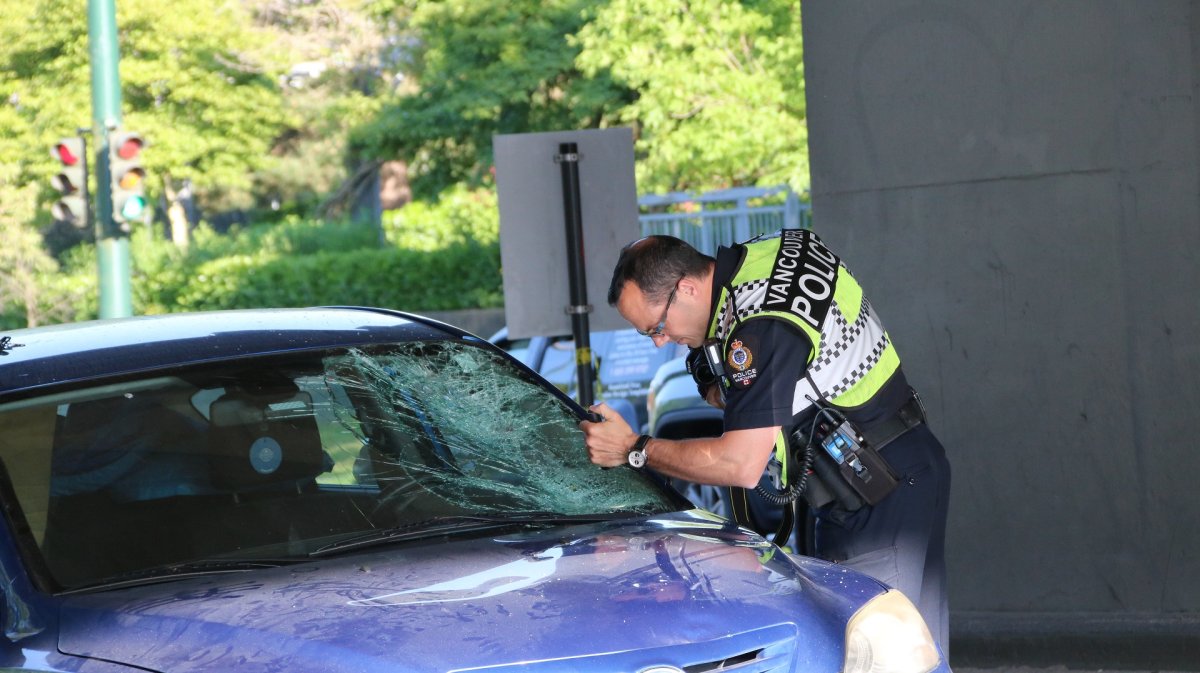 Police inspecting a blue Mazda at the scene of a crash on Granville Island Sunday evening.