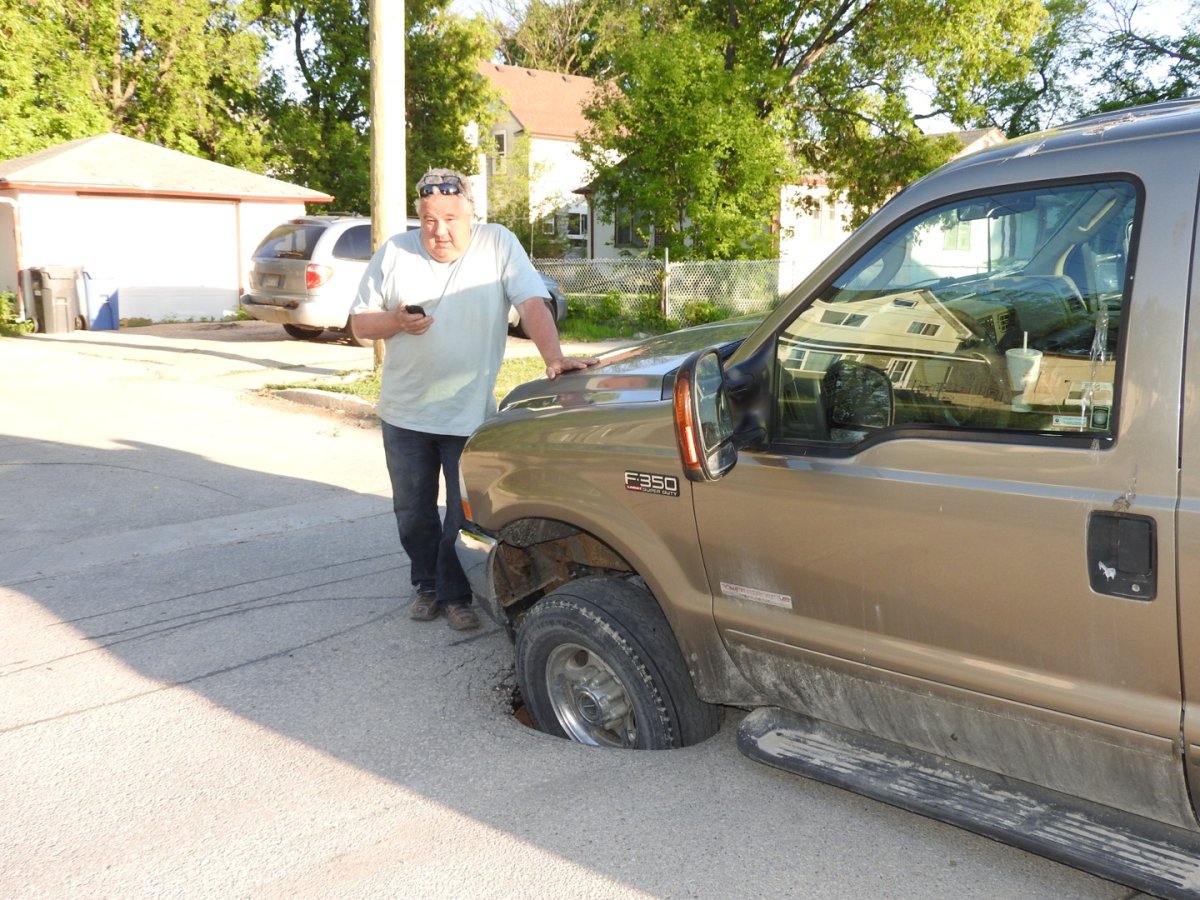Farley Pollock leans on his truck after it fell into a sinkhole Wednesday evening. 
