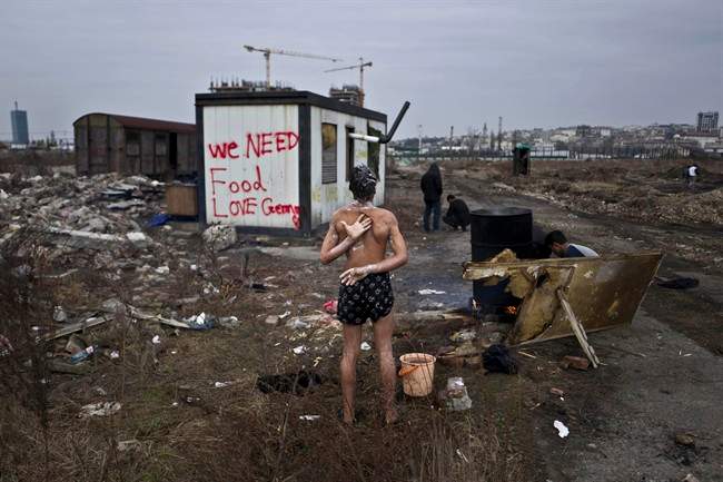In this Saturday, Feb. 11, 2017 file photo, a 14-year old unaccompanied minor, a migrant from Afghanistan, showers on a cold day near an old train carriage. 