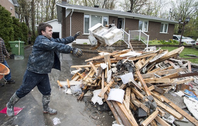 David Samuelson throws debris from his flooded house onto a pile on his driveway in the Pierrefonds borough of Montreal Sunday, May 14, 2017.  Montreal firefighters announced a fundraising blitz to help victims dealing with the aftermath of May's devastating floods. Tuesday, June 13, 2017.