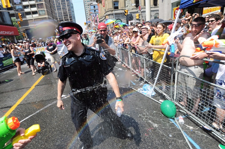 A police officer is sprayed by parade goers during the WorldPride Parade in Toronto, Ontario June 29, 2014.