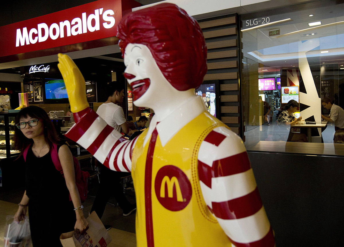 In this July 31, 2014, file photo, a customer walks past a statue of Ronald McDonald on display outside a McDonald's restaurant in Beijing. 