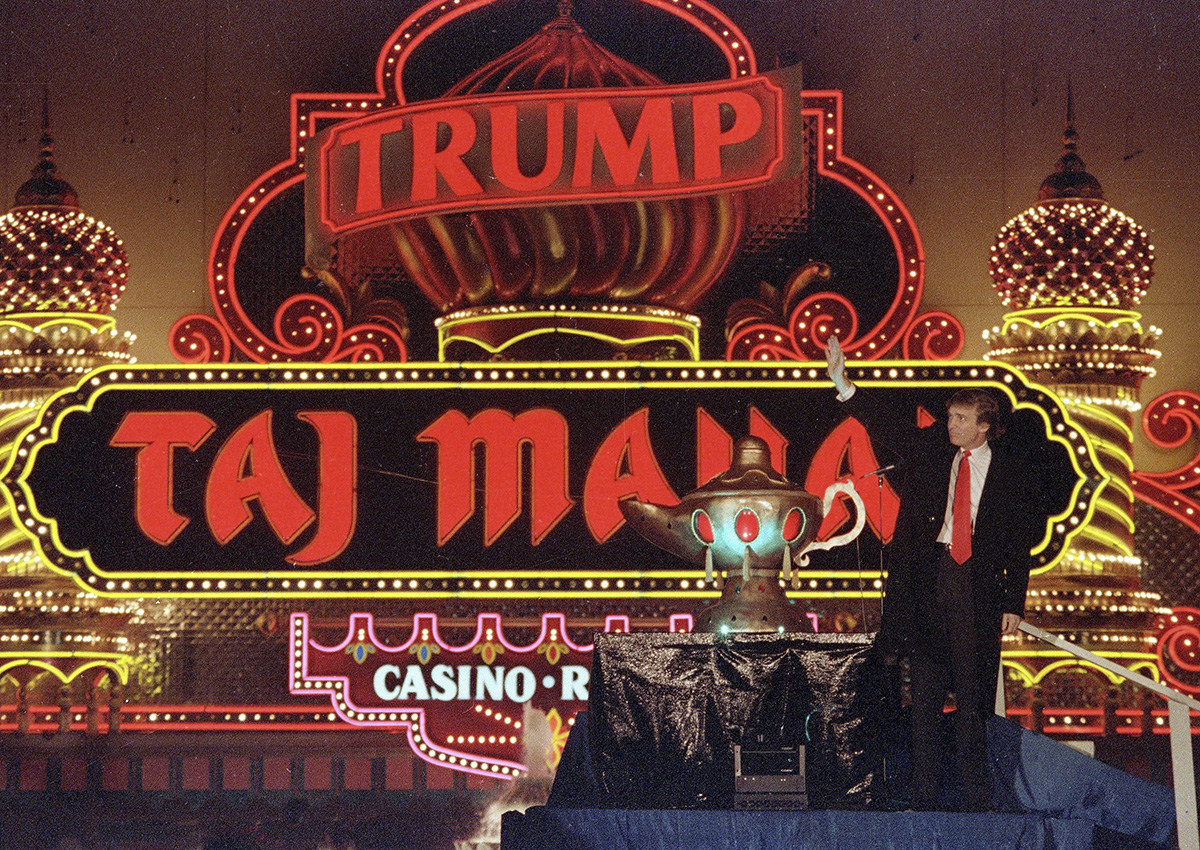 In this April 5, 1990 file photo, Donald Trump stands next to a genie lamp as the lights of his Trump Taj Mahal Casino Resort mark its grand opening in Atlantic City, N.J.