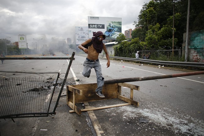 A demonstrator jumps over a barricade during a national sit-in against President Nicolas Maduro, in Caracas, Venezuela.