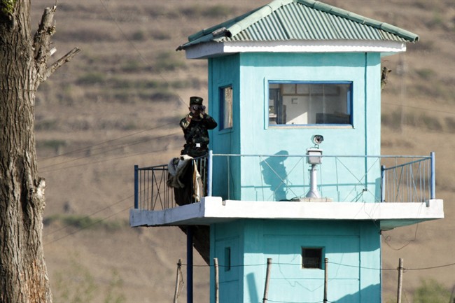 In this Wednesday, May 3, 2017 photo, a North Korean soldier looks through a pair of binoculars as he stands at a guard tower on the border near Chongsu in North Korea's North Pyongan Province.