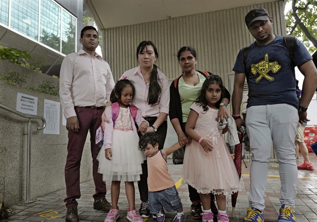 Asylum seekers, from left: Ajith Pushpa Kumara, Vanessa Mae Rodel and her daughter Keana, Nadeeka Dilrukshi Nonis and her son Dinath and daughter Sethmundi Kellapatha, and Supun Thilina Kellapatha, pose outside the building of Hong Kong’s immigration department in Hong Kong.