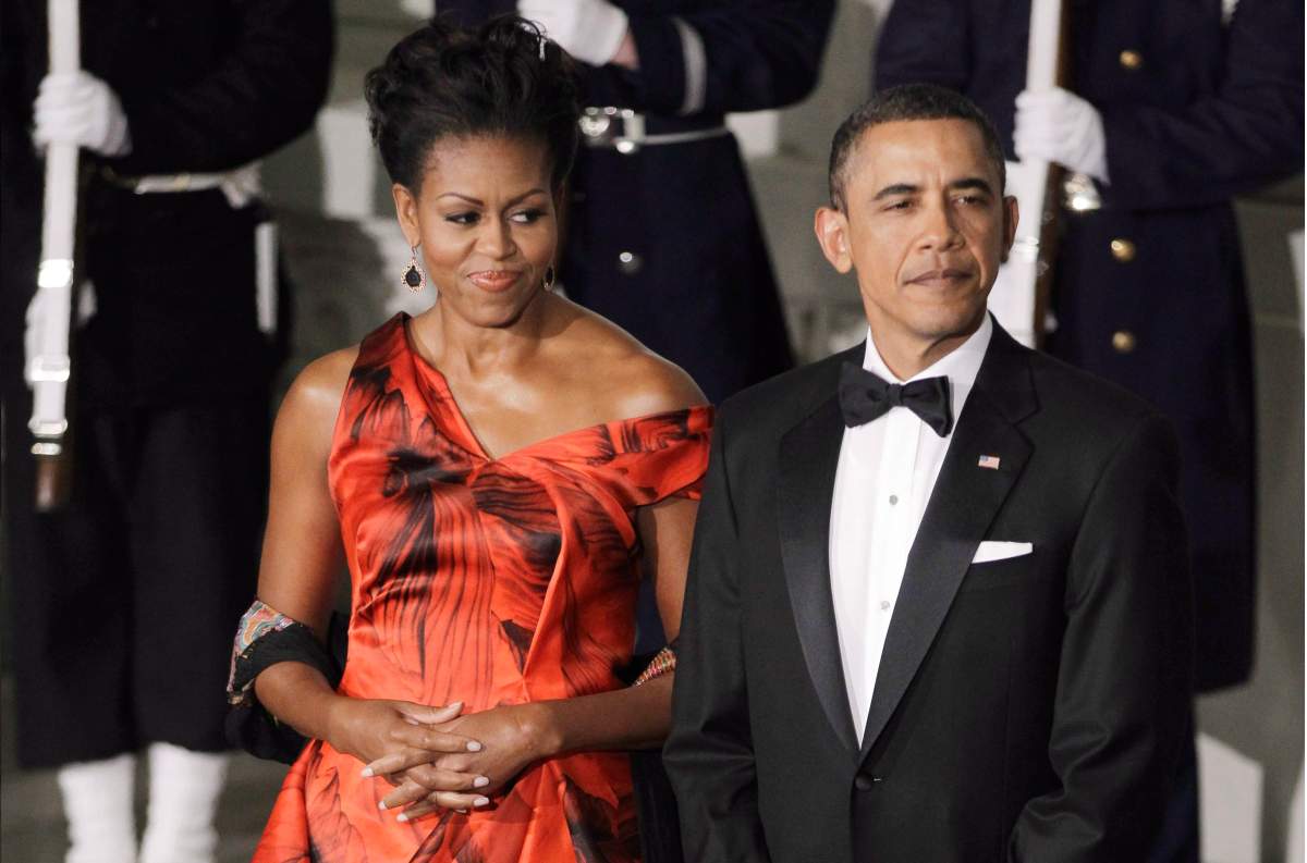This Jan. 19, 2011 file photo shows then-president Barack Obama and first lady Michelle Obama at the North Portico of the White House in Washington as they wait the arrival of China’s President Hu Jintao for the State Dinner. Michelle Obama is wearing a fiery red gown designed by Alexander McQueen.