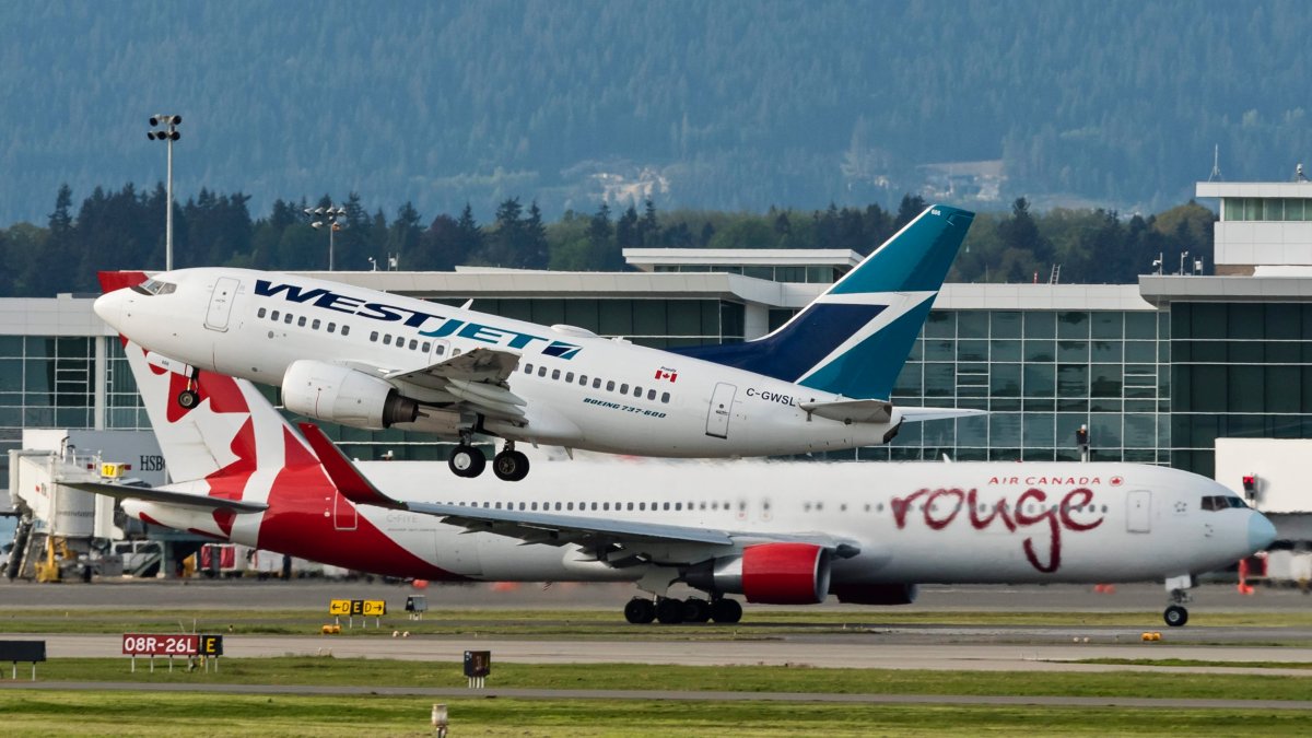 A WestJet Boeing 737 (737-600) airliner takes off from Vancouver International Airport, Richmond, B.C., April 27, 2016. In the background an Air Canada rouge Boeing 767 (767-300ER) taxies along the tarmac.