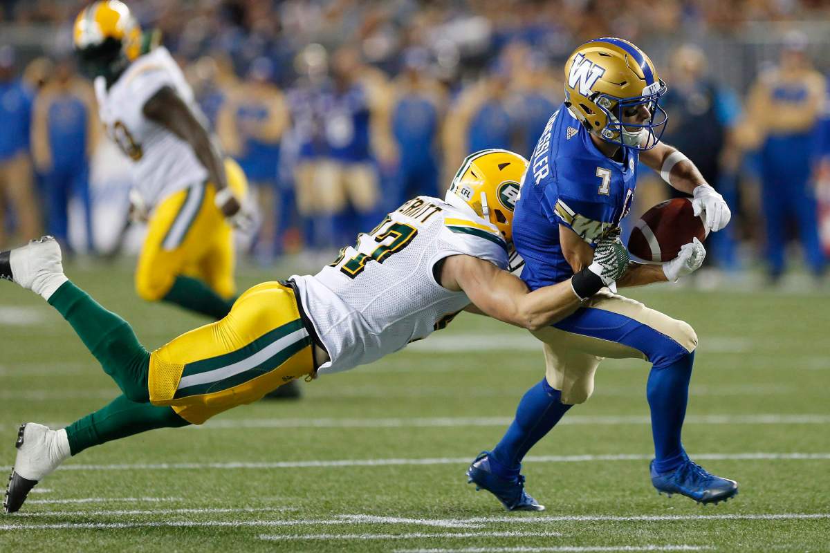 Edmonton Eskimos' JC Sherritt (47) strips the ball from the hands of Winnipeg Blue Bombers' Weston Dressler (7) during the first half of CFL action in Winnipeg Friday, Sept. 30, 2016.