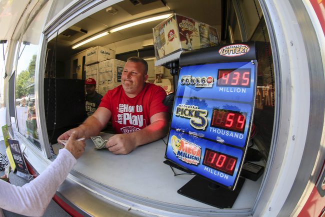 Chris Raff of Lincoln, Neb., hands a Powerball ticket to a customer in Omaha, Neb., Saturday, June 10, 2017.