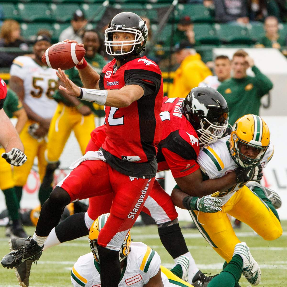 Calgary Stampeders quarterback Ricky Stanzi (12) gets the ball out as Justin Renfrow (64) wraps up Edmonton Eskimos Rykeem Yates (99) during second half CFL pre-season action in Edmonton, Alta., on Sunday June 11, 2017. The Stampeders won 36-35. THE CANADIAN PRESS/Amber Bracken