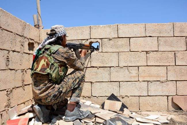 A soldier aims an automatic rifle through a peephole in a wall at Raqqa city, Syria, 11 June 2017. 

