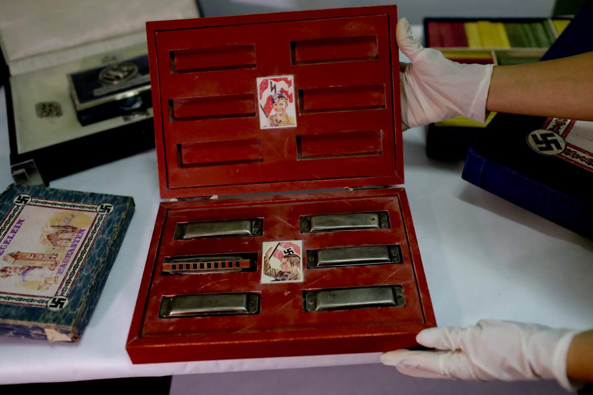 A member of the federal police shows a box with swastikas containing harmonicas for children at the Interpol headquarters in Buenos Aires, Argentina, Friday, June 16, 2017.