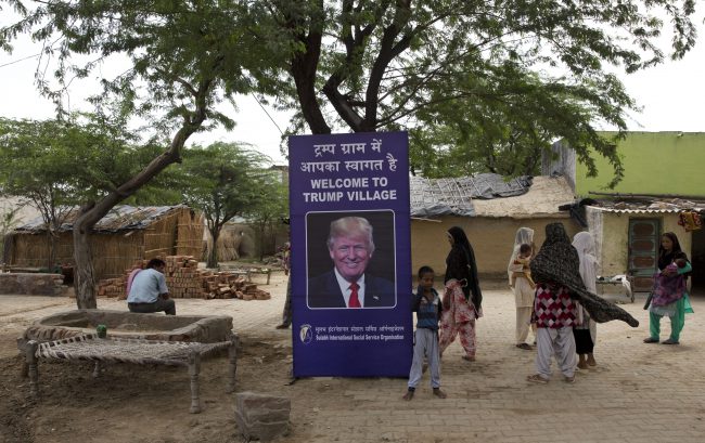 Indian village women stand next to a photograph of U.S. President Donald Trump displayed in Trump Sulabh Village, in Maroda, India, June 23, 2017.