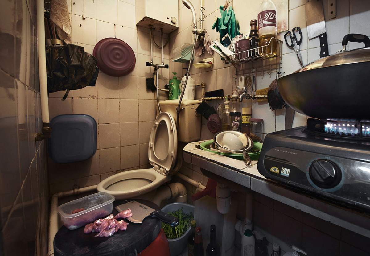 Meat being cut on a stool in a shared kitchen-toilet space in Hong Kong.