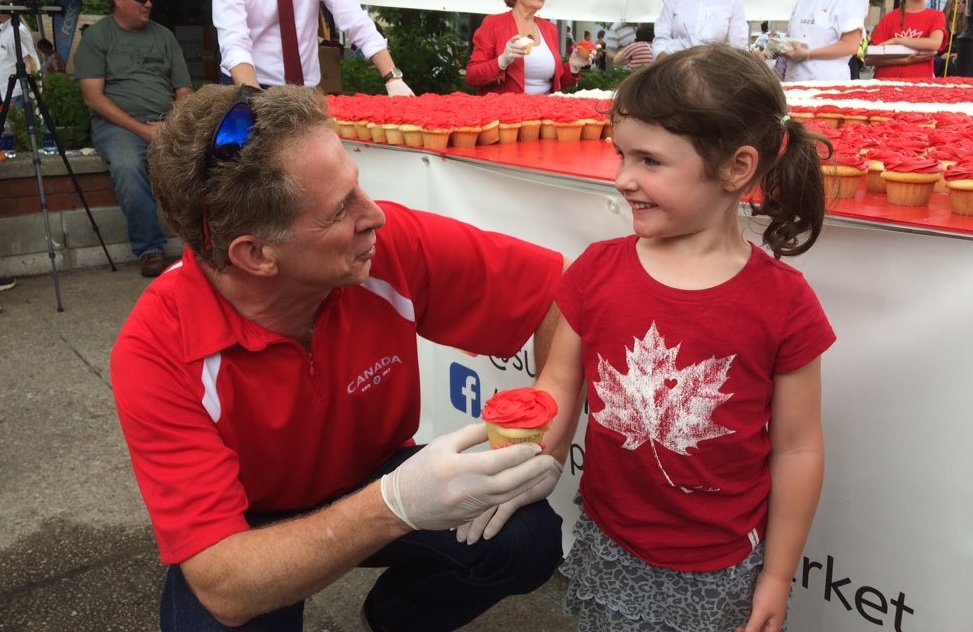 Four-year-old Anna gets one of 3,000 cupcakes from Coun. Paul Hubert after Sesquifest's opening ceremony on June 30, 2017.