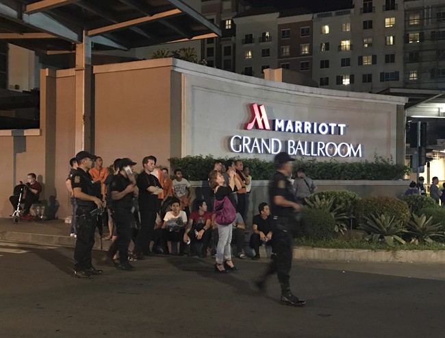 Armed security officers and onlookers gather outside a hotel at the Resorts World Manila complex, early Friday, June 2, 2017, in Manila, Philippines.