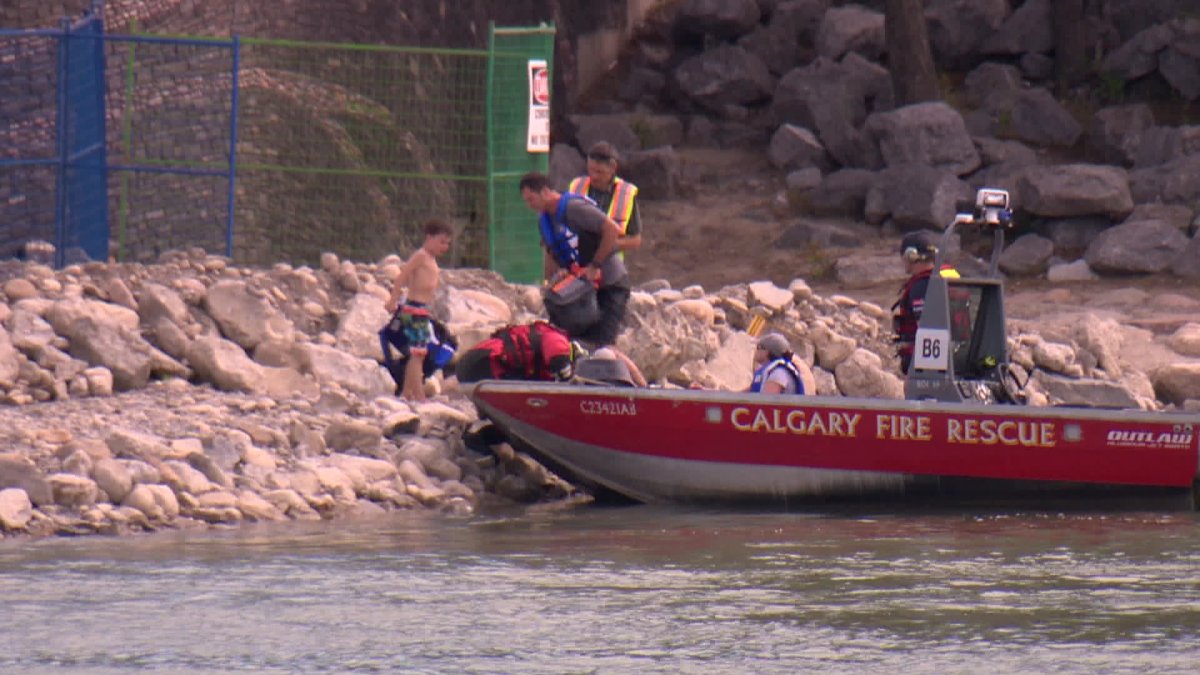 Rescue crews bringing people to safety after their boat flipped on the Bow River. 