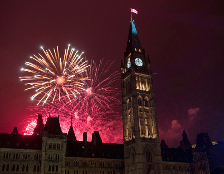 Fireworks light up the sky red behind the Peace Tower