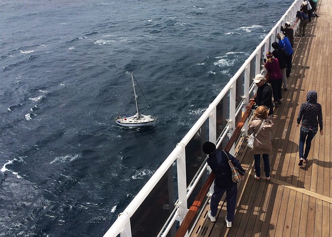 Passengers aboard the cruise liner Queen Mary 2 look on as they approach a British sailor on a disabled yacht in the Atlantic Ocean on Saturday, June 10, 2017. All crew aboard four storm-battered vessels that had been racing across the Atlantic Ocean are safe, the Halifax-based joint rescue co-ordination centre said Saturday. A spokeswoman for the centre said crew on two sailboats that put out distress calls were rescued Saturday morning, while a third boat made its way to calmer waters.