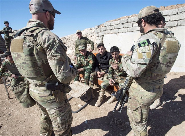 Canadian special forces soldiers, left and right, speak with Peshmerga fighters at an observation post, Monday, Feb. 20, 2017 in northern Iraq. 