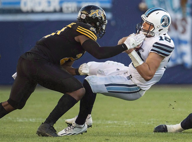 Hamilton Tiger-Cats linebacker Simoni Lawrence (21) tackles Toronto Argonauts quarterback Dan LeFevour (18) during second half CFL football action in Toronto on Sunday, September 11, 2016. Training camp might be a necessary evil for most veteran CFL players, but it sustains Lawrence.".