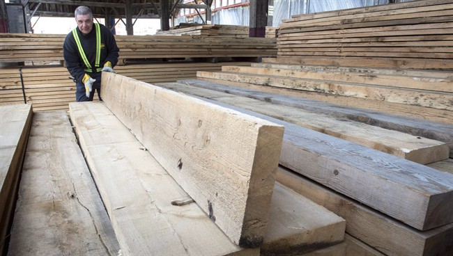 A worker tidies up the wood pile at a lumber yard Tuesday, April 25, 2017 in Montreal. 