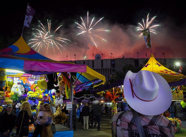 A visitor watches the fireworks display from the midway at the Calgary Stampede in Calgary, Saturday, July 9, 2016. 