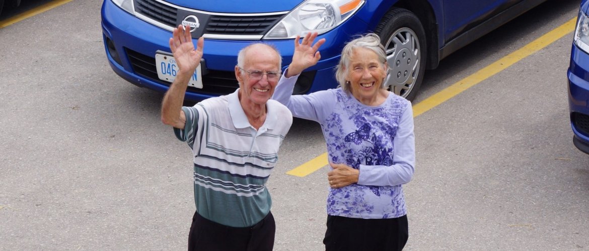 Bll Heeman and wife Susan stand together, waving at a crowd. 