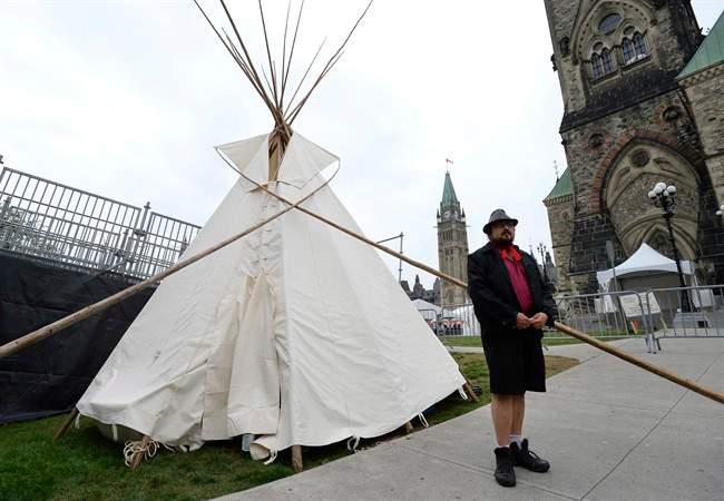 A man stands outside a large teepee erected by indigenous demonstrators to kick off a four-day Canada Day protest in front of Parliament Hill in Ottawa on Thursday, June 29, 2017.