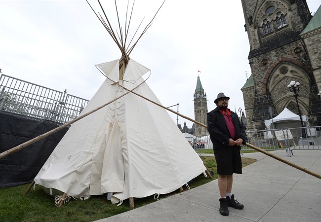 A man stands outside a large teepee erected by indigenous demonstrators to kick off a four-day Canada Day protest in front of Parliament Hill in Ottawa on Thursday, June 29, 2017.