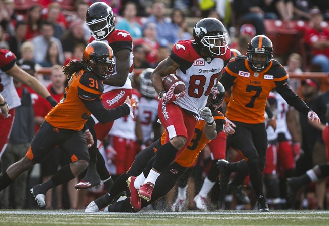BC Lions' Josh Harris, left, and Matt Bucknor, right, look on as Calgary Stampeders' Jamal Nixon runs the ball during CFL pre-season football action in Calgary, Tuesday, June 6, 2017.