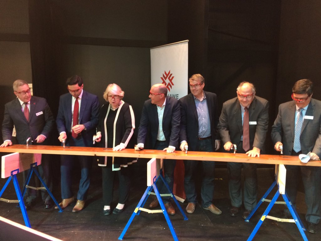 School officials and political representatives prepare to hammer nails into a wooden joist from the old Kingsmill's building. 