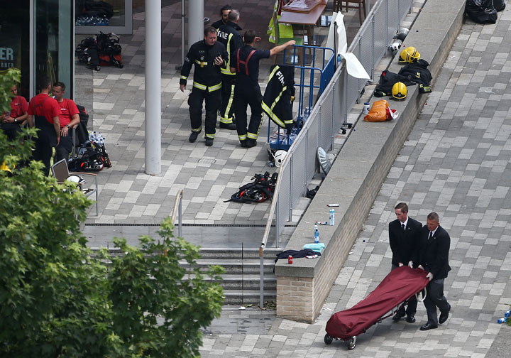 A bag on a stretcher is wheeled away from a tower block