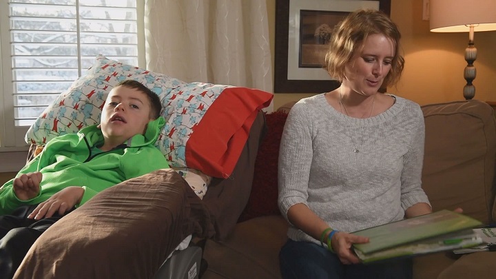 Stephanie Paravan sits next to her son, Matthew, holding the binder she assembled to keep track of his medical records.